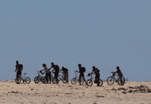 What’s the net worth of your cycling group? Group of people cycling and pushing their bike off road